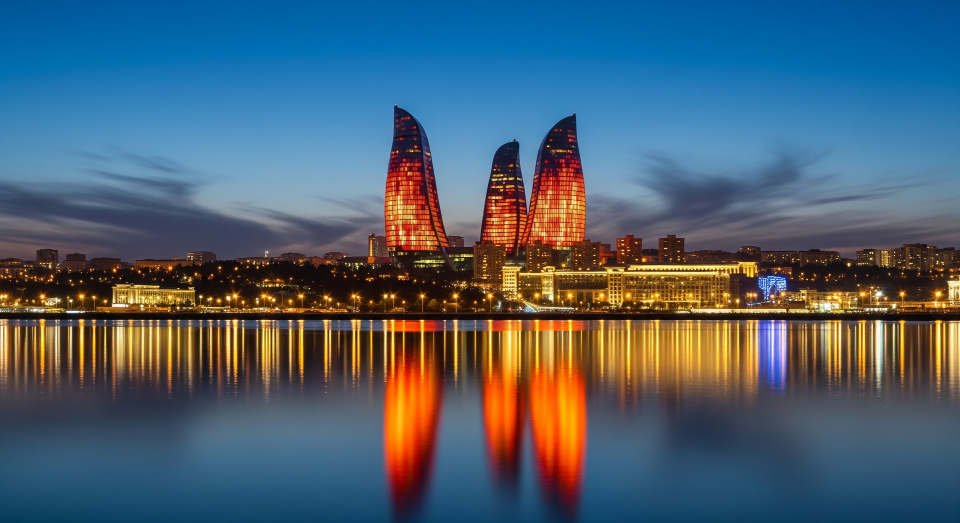Flame Towers illuminated at night reflecting over Baku Bay