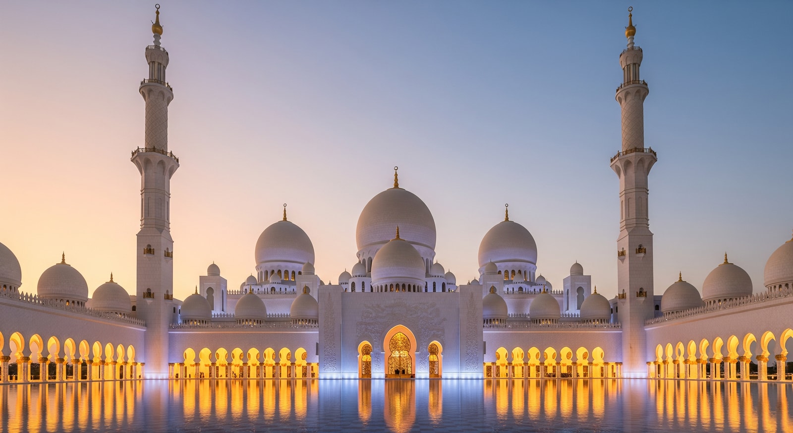Sheikh Zayed Grand Mosque in Abu Dhabi with white marble domes and minarets reflecting in water pool