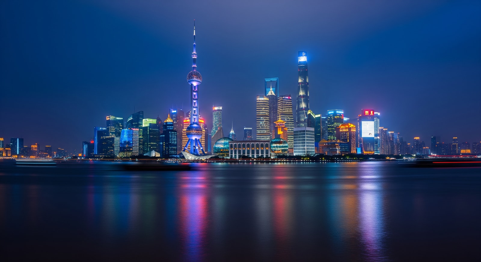 Shanghai skyline at night with Pudong skyscrapers including Oriental Pearl Tower illuminated and reflected in Huangpu River