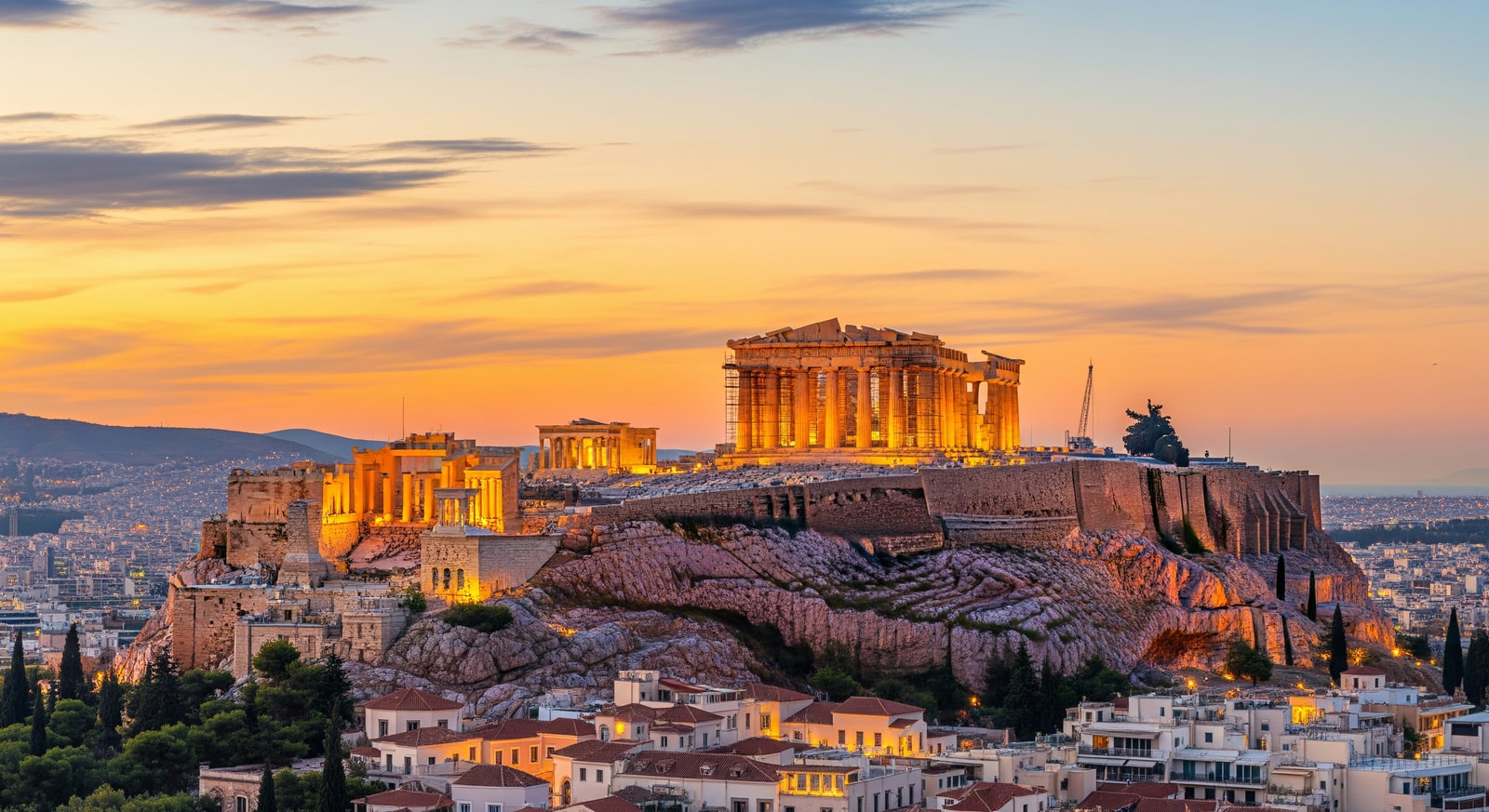 The Parthenon temple atop the Acropolis in Athens illuminated at golden hour with city views below