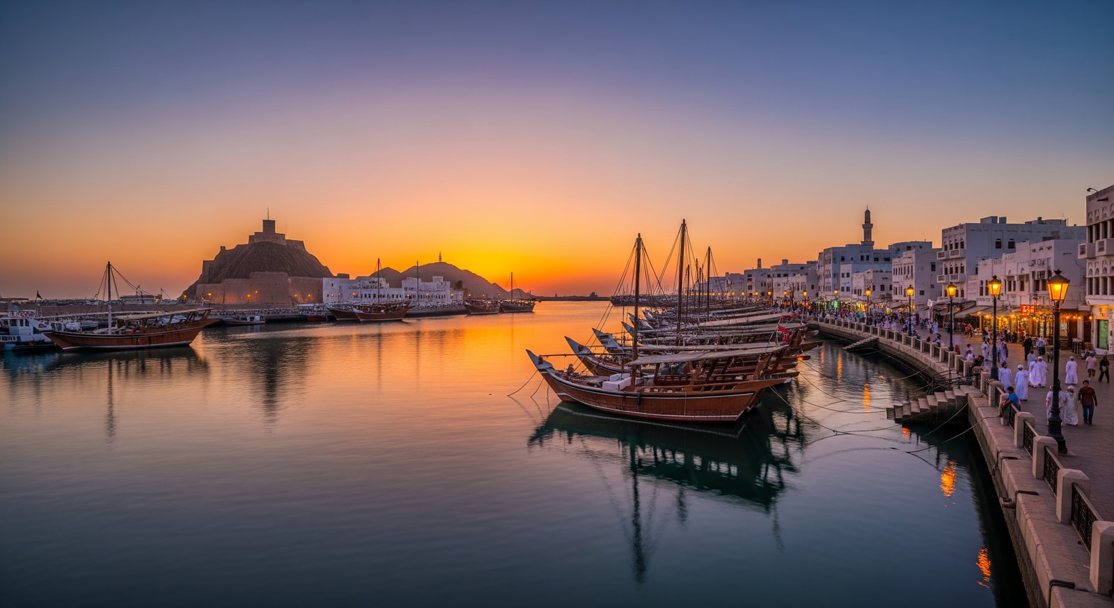 Panoramic view of Muscat harbor with traditional boats and the Mutrah Corniche at sunset