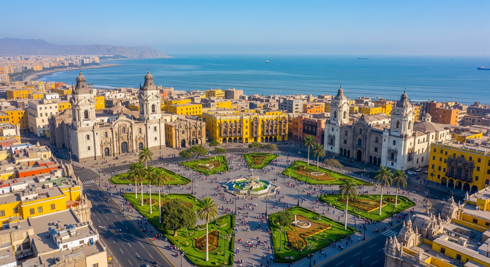 Aerial view of Lima's historic Plaza de Armas with colonial architecture and the Pacific Ocean coastline in the distance