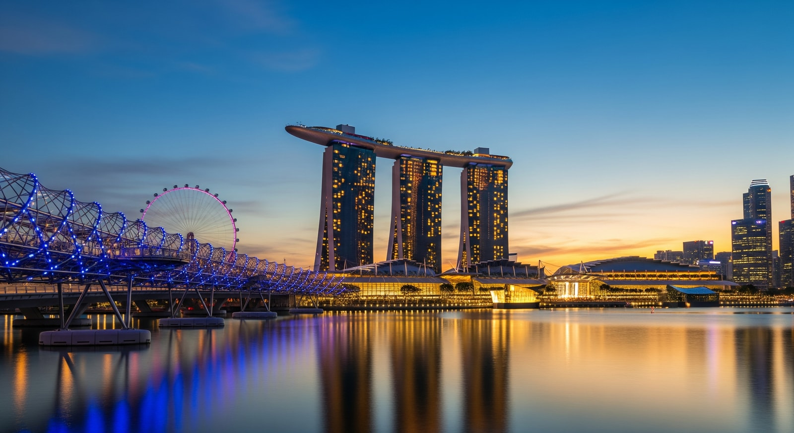 Iconic Marina Bay Sands hotel with the Helix Bridge and Singapore Flyer in the evening skyline