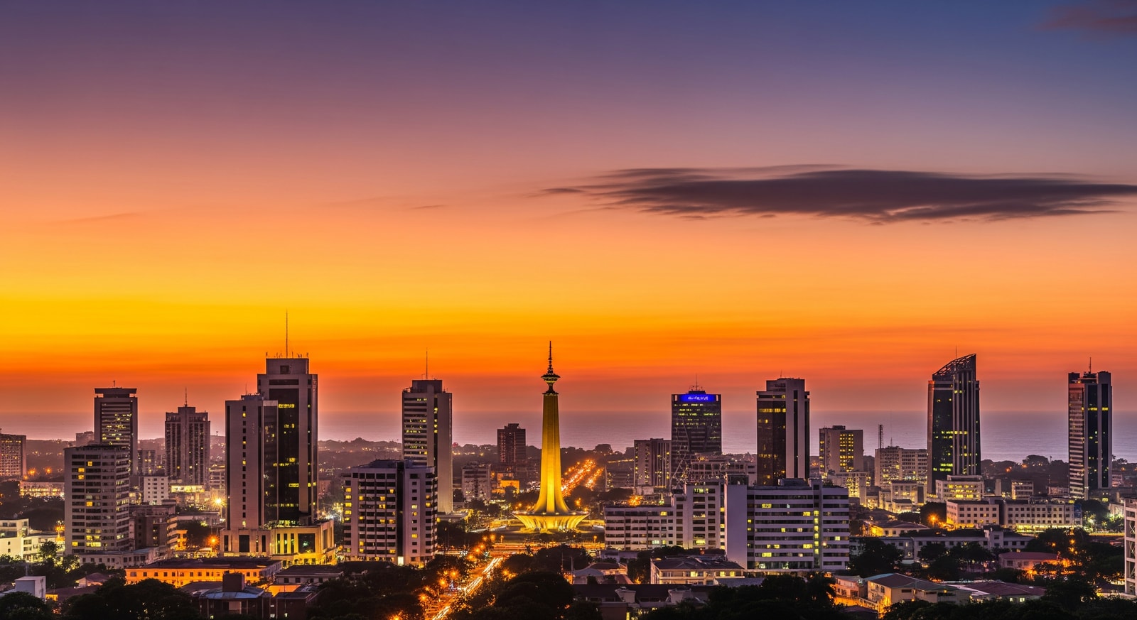 Panoramic view of Lome city skyline with modern buildings and the Independence Monument at sunset