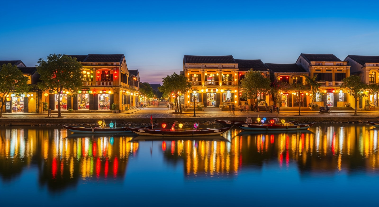 Colorful lanterns illuminating the ancient town of Hoi An with traditional yellow buildings reflected in Thu Bon River at dusk